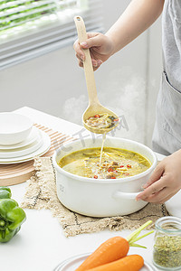 做饭白天做饭的女人厨房用勺子舀菜摄影图配图