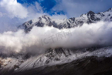 云雾中的雪山山峰摄影图配图