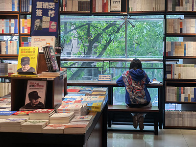 书店读书的人摄影照片_书店看书的人下午人物室内看书摄影图配图