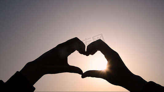 实拍情侣夕阳下比爱心意境剪影