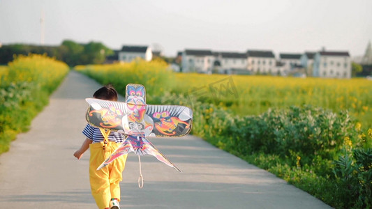 清明风筝摄影照片_春天油菜花儿童男孩奔跑的背影