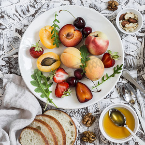 夏季水果-杏子，桃子，李子，樱桃，草莓和蜂蜜，核桃光石背景上