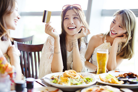 说中文摄影照片_青年组显示信用卡并在餐厅聊天