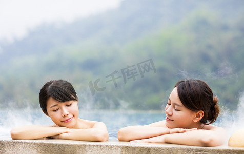 室外温泉摄影照片_幸福的年轻女人在温泉中休息