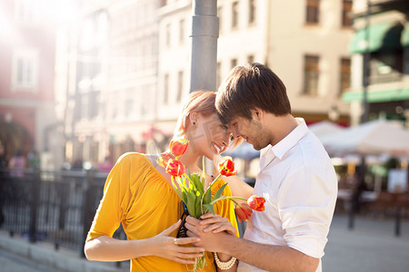 女孩拿鲜花摄影照片_在街上浪漫的情侣手拿鲜花