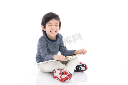 日本教育摄影照片_读一本书孤立的白色背景上的可爱亚洲男孩