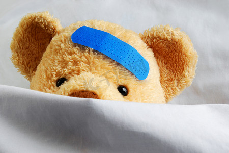 躺在床上摄影照片_躺在床上的泰迪熊创可贴