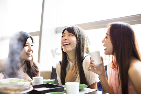 火锅摄影照片_快乐的年轻妇女组吃火锅