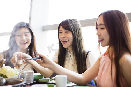 快乐的年轻妇女组吃火锅 
