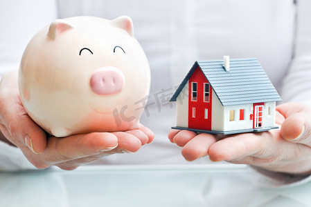 Hands with piggy bank and house model