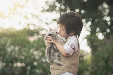 卡通小猫猫背影摄影照片_亚洲男孩亲吻美国短头发的小猫 