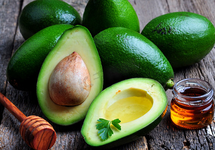 拍黄瓜摄影照片_Fresh avocado with olive oil and honey on wooden background
