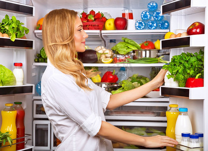 室内冰箱摄影照片_打开冰箱挑选各种蔬菜水果的漂亮女人