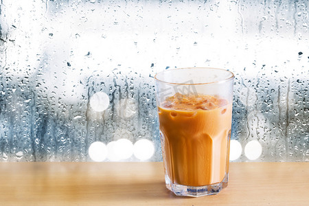 食物冰摄影照片_对木制冰奶茶和滴的雨水镜子背景