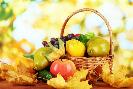 不同种类的水果和蔬菜，黄色的叶子在篮子上明亮的背景表格