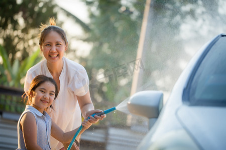 亚洲孩子摄影照片_快乐的亚洲女孩与她的母亲在家里洗车