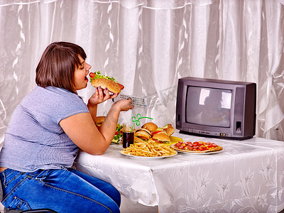 热狗摄影照片_女人吃快餐和看电视.