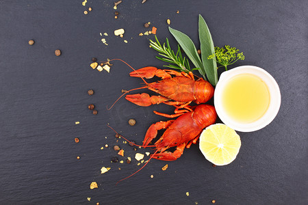 or摄影照片_Delicious fresh lobster on dark vintage background. Seafood with aromatic herbs, spices and vegetables - healthy food, diet or cooking concept