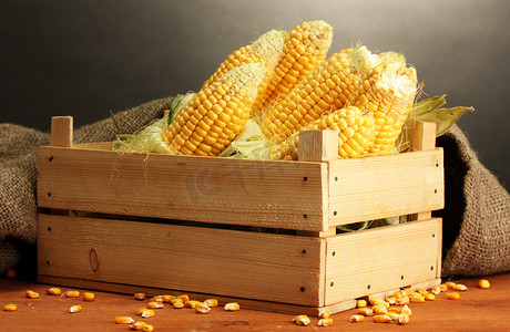 黄色框摄影照片_在框中，木桌上，灰色的背景上新鲜玉米
