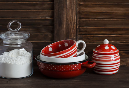 红色家庭用具摄影照片_Kitchen still life. Glass jar with flour and vintage crockery -  mug, bowl, jar and pan