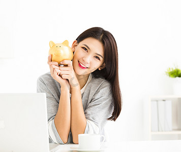 微笑的年轻女子捧着存钱罐