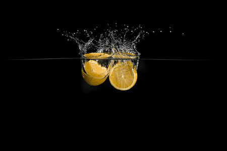 飞溅的水摄影照片_水在黑色背景上的柠檬