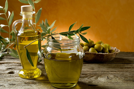 金色瓶子摄影照片_橄榄油对木材背景