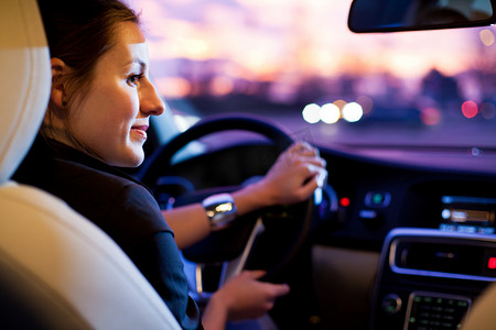 夜间交通安全摄影照片_在一个城市夜间驾驶他的现代车的女人