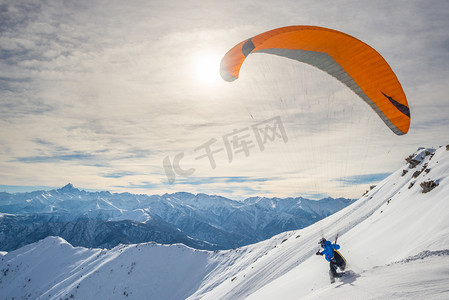 空气运动摄影照片_滑翔伞从雪坡上启动