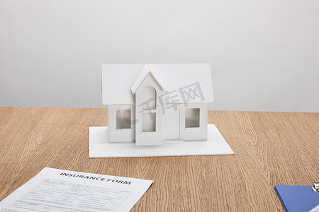社会行动摄影照片_餐桌上保险形式与小房子模型的特写视图