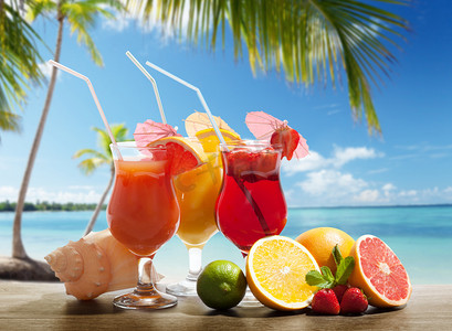水果摄影照片_在海滩上的 cocktaisl 和热带水果