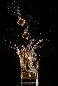 溅起水花摄影照片_冰块掉进威士忌溅起水花