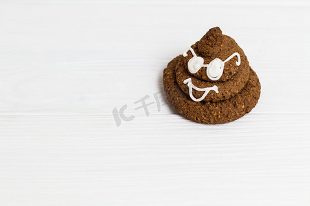 滑稽摄影照片_滑稽的船尾表情符号巧克力饼干与白色装饰和眼镜。可爱的食物甜点在右角。文本的免费位置。Copyspace.