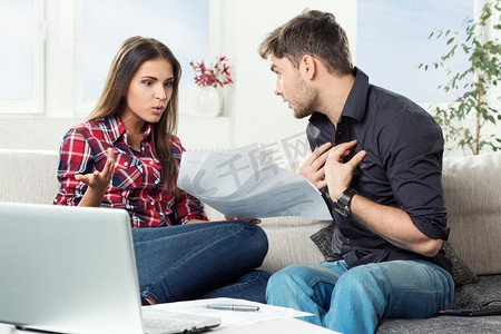 情感不合摄影照片_在客套厅争吵的年轻夫妇与未付帐单