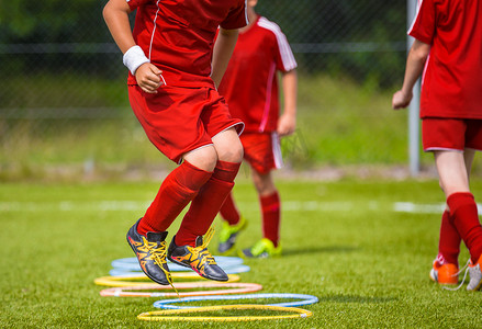 儿童身体活动摄影照片_年轻的足球运动员在球场上设备动态跳跃式的足球训练