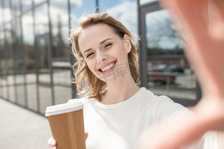 年轻的女性手拿咖啡与镜头互动