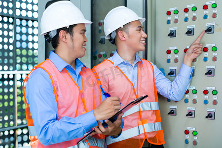 Asian technicians at panel on construction site