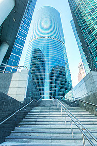 蓝色商务几何背景摄影照片_要钢浅蓝色背景的玻璃高高层建筑未来的摩天大楼商业现代城市的全景和前瞻性的广角视图。成功的工业建筑的业务概念