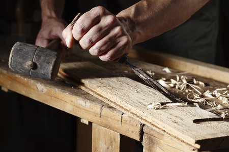 工匠工具摄影照片_木匠手使用凿子和锤子
