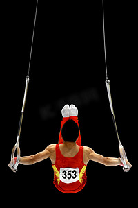 体操室内摄影照片_体操运动员在吊环上执行