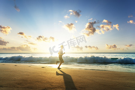 欧美体育摄影照片_日落时在热带海滩上奔跑的人