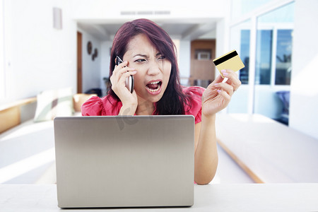坐在电脑前在线购物打电话的失望的女人