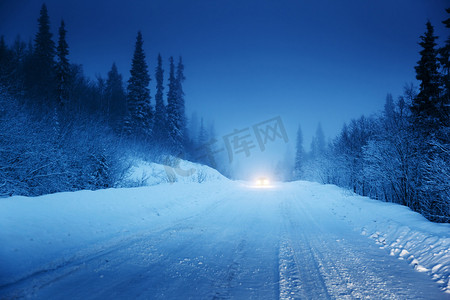 雪摄影照片_汽车和冬季路在森林里的灯光