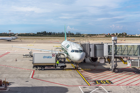 客机摄影照片_ALITALIA飞机停在候机楼。飞行前的装载和维修操作
