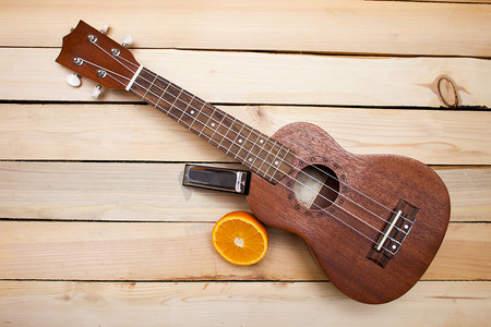 夏威夷四弦琴吉他与多汁橙橙子片和木背景上的铁唇手风琴