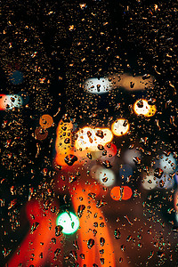 关闭窗口上的雨滴视图和散景城市灯光背景