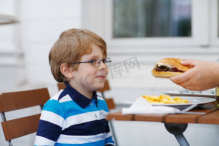 无聊暑假摄影照片_小男孩吃快餐： 法式炸薯条和汉堡