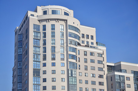 多层的办公大楼有很多玻璃窗户的米色，背景为纯蓝色的天空。新建的写字楼出租