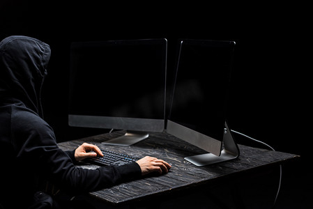 黑客使用计算机鼠标，看着计算机监视器，屏幕空白，与黑色隔离 