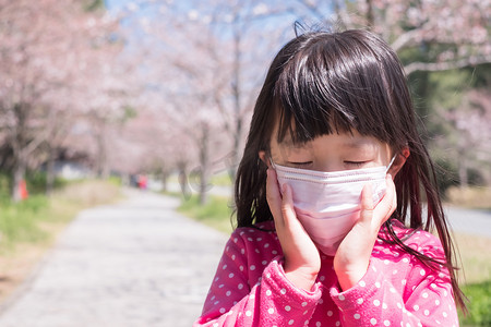 儿单戴口罩摄影照片_戴着口罩在公园游玩的小女孩